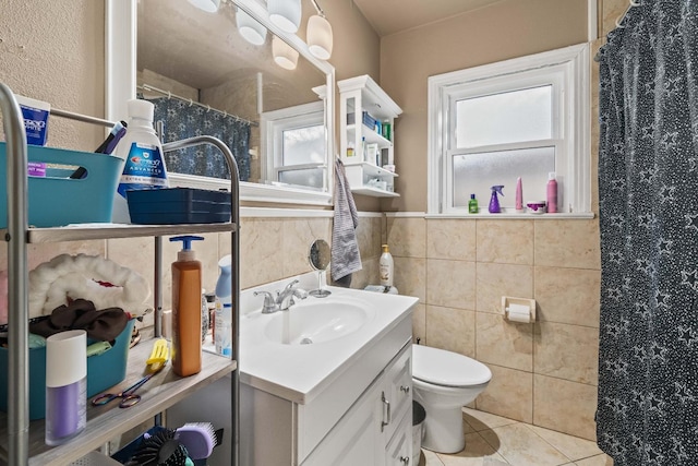 bathroom featuring a healthy amount of sunlight, tile patterned floors, tile walls, and vanity