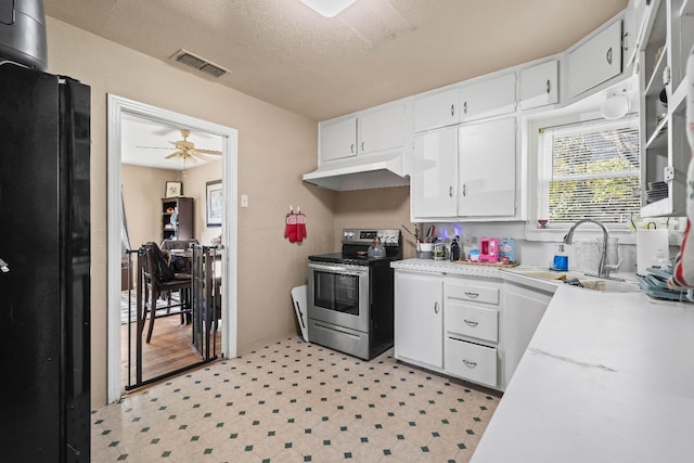 kitchen featuring sink, stainless steel range with electric cooktop, black fridge, a textured ceiling, and white cabinets