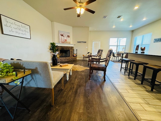 living room with wood-type flooring, ceiling fan, and a fireplace