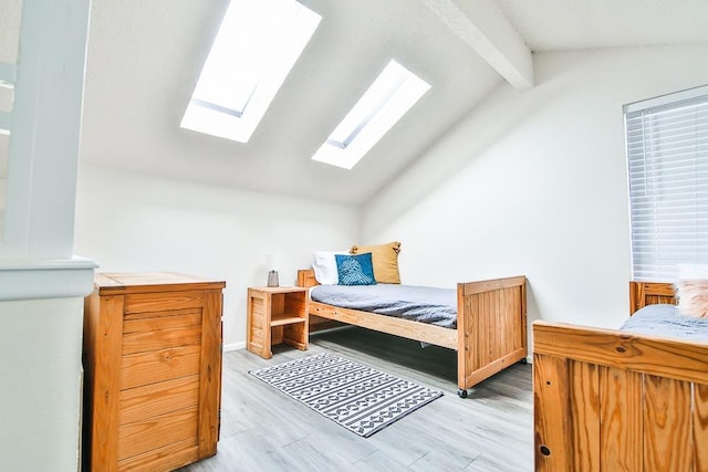 bedroom featuring lofted ceiling with beams and light hardwood / wood-style floors