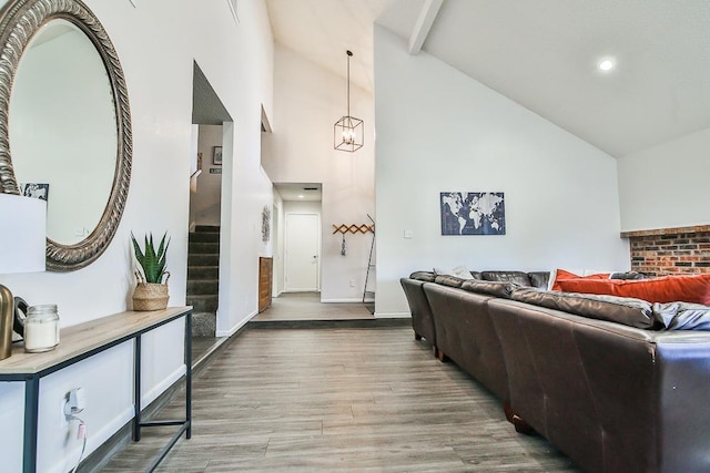 living room featuring hardwood / wood-style flooring, an inviting chandelier, high vaulted ceiling, and beam ceiling