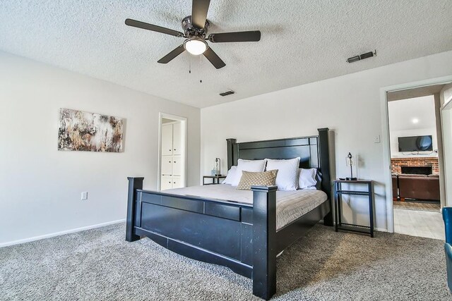 carpeted bedroom featuring ceiling fan, ensuite bathroom, and a textured ceiling