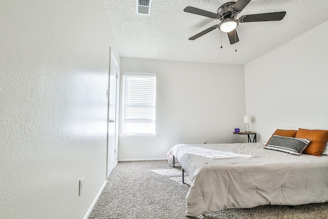 carpeted bedroom with ceiling fan and a textured ceiling