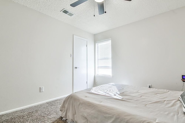 bedroom with ceiling fan, carpet flooring, and a textured ceiling