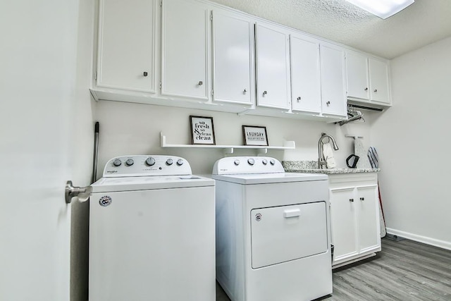 laundry room with cabinets, light hardwood / wood-style flooring, washer and dryer, and a textured ceiling