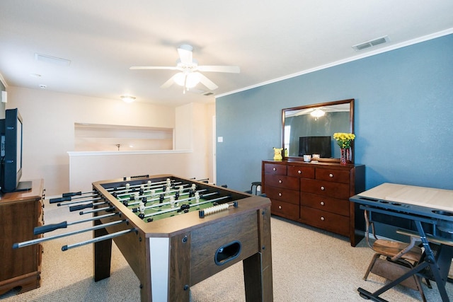 rec room with ceiling fan, ornamental molding, and light carpet