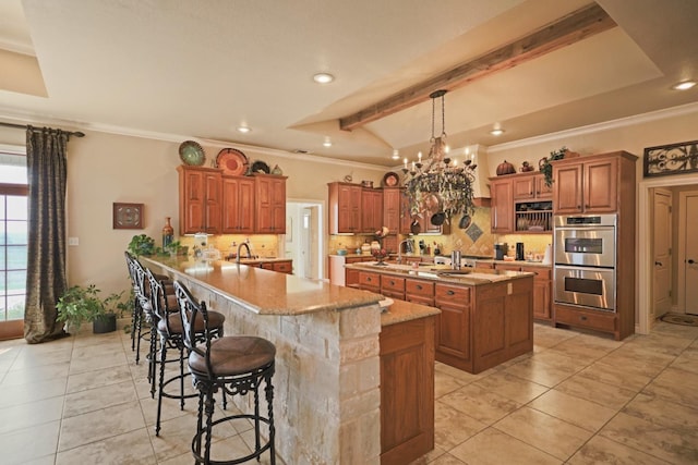 kitchen featuring double oven, backsplash, kitchen peninsula, and a breakfast bar