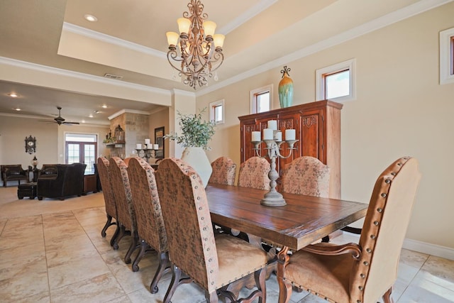 dining space with ornamental molding, ceiling fan with notable chandelier, and a tray ceiling