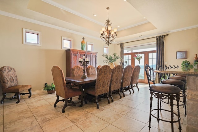 dining room with a notable chandelier, a tray ceiling, ornamental molding, and french doors