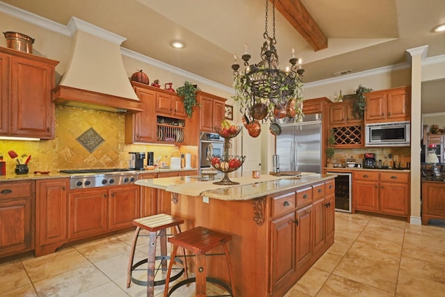 kitchen with premium range hood, an island with sink, beverage cooler, ornamental molding, and built in appliances