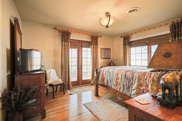 bedroom featuring french doors, multiple windows, and light wood-type flooring