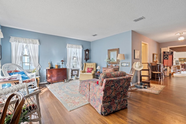 living room with wood-type flooring, plenty of natural light, and a textured ceiling