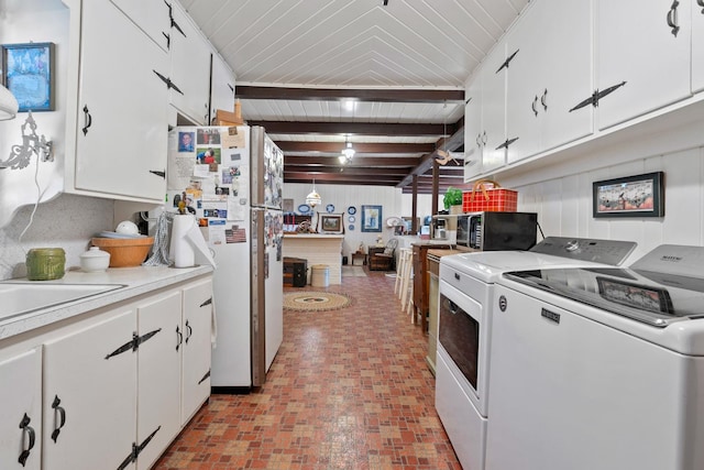 kitchen with white cabinetry, white refrigerator, washer and dryer, and beamed ceiling