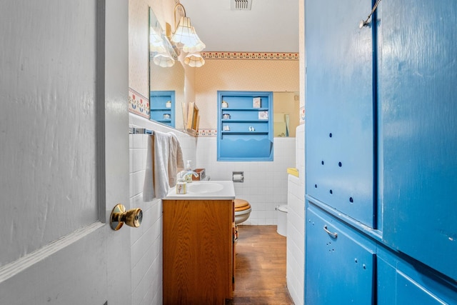 bathroom with hardwood / wood-style floors, vanity, tile walls, and toilet