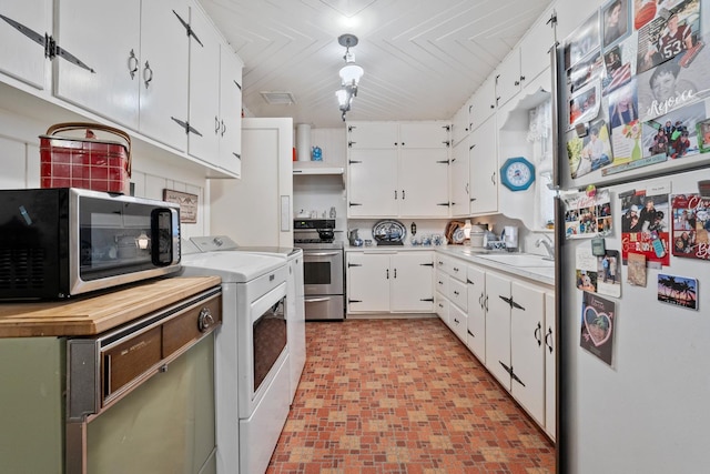 kitchen featuring appliances with stainless steel finishes, washer / dryer, sink, and white cabinets