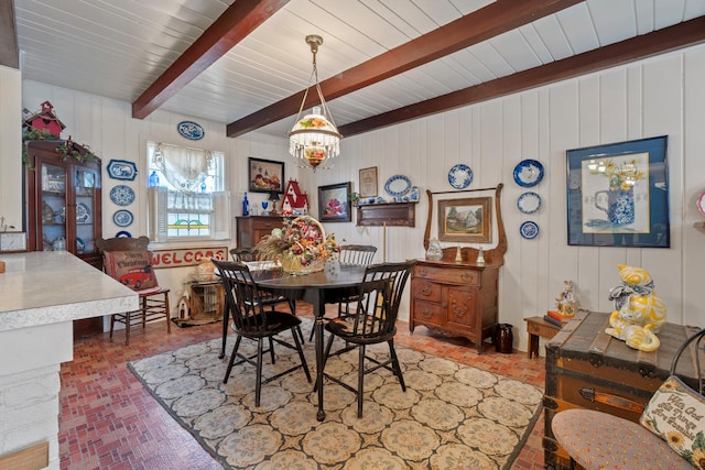 dining space with beam ceiling and a chandelier