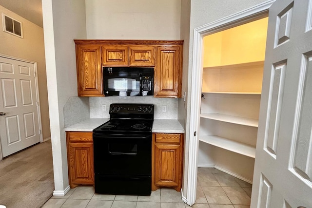 kitchen featuring tasteful backsplash, light tile patterned floors, and black appliances