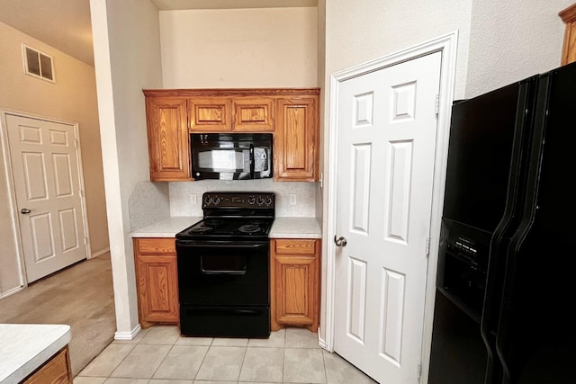 kitchen with light tile patterned flooring and black appliances