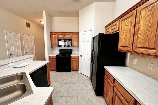 kitchen with backsplash, light tile patterned floors, black appliances, and sink