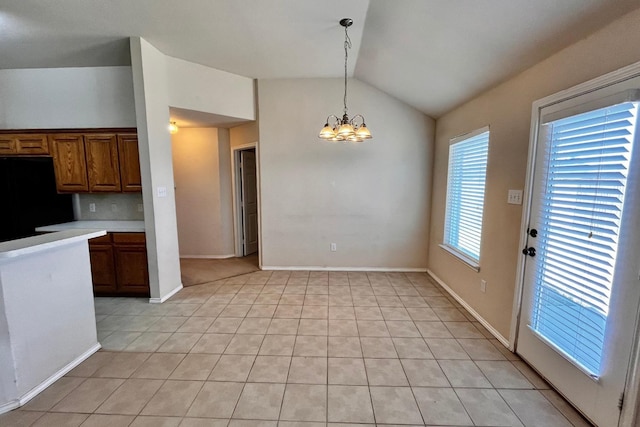 kitchen with lofted ceiling, light tile patterned floors, an inviting chandelier, fridge, and decorative light fixtures