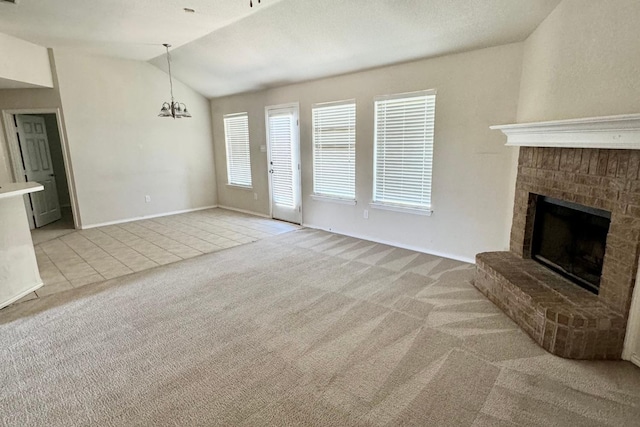 unfurnished living room featuring light carpet, a brick fireplace, lofted ceiling, and an inviting chandelier