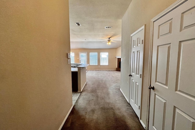 corridor featuring light colored carpet and a textured ceiling