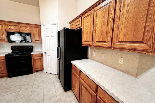 kitchen with light tile patterned flooring, decorative backsplash, and black appliances