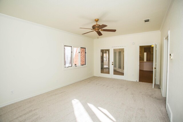 empty room featuring crown molding, light colored carpet, ceiling fan, and french doors