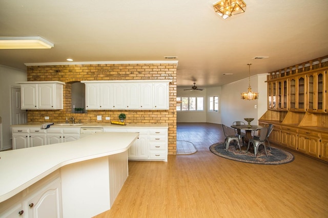 kitchen with pendant lighting, sink, white cabinets, ceiling fan with notable chandelier, and light wood-type flooring