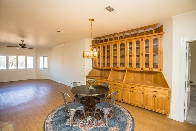 dining area featuring ceiling fan with notable chandelier, ornamental molding, and light hardwood / wood-style floors