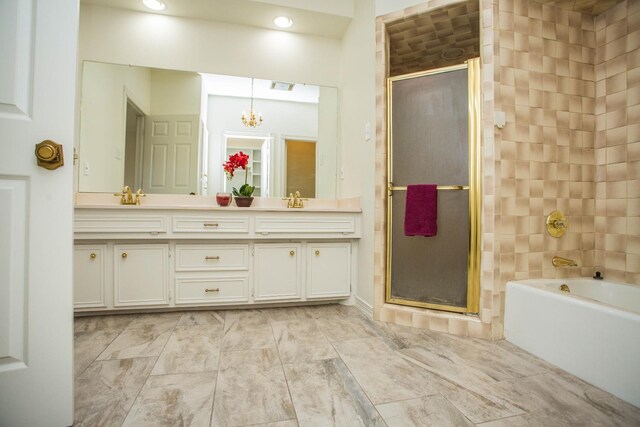 bathroom with independent shower and bath, vanity, and an inviting chandelier