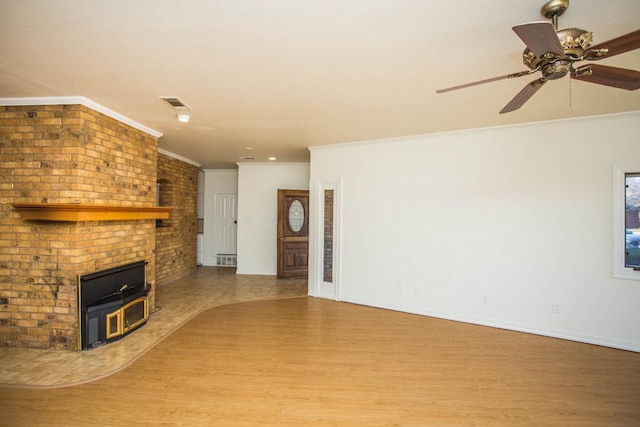 unfurnished living room with crown molding, wood-type flooring, ceiling fan, and a wood stove