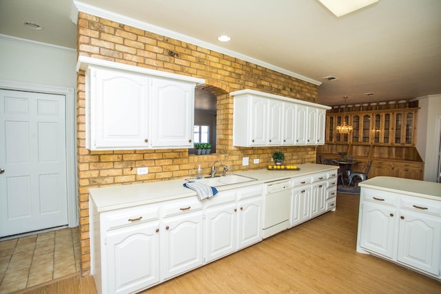 kitchen with sink, crown molding, dishwasher, brick wall, and white cabinets