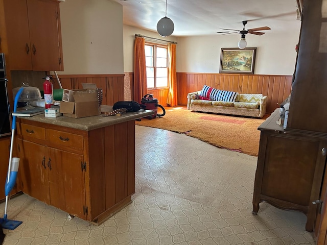 kitchen featuring kitchen peninsula, oven, ceiling fan, and wood walls