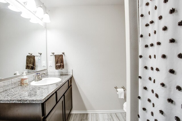 bathroom with a shower with shower curtain, vanity, toilet, and hardwood / wood-style floors