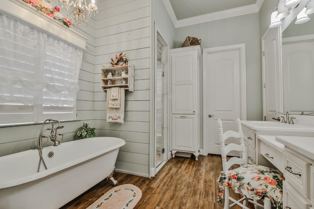 bathroom featuring a chandelier, hardwood / wood-style flooring, ornamental molding, vanity, and a washtub