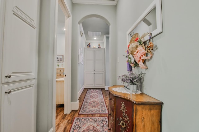 corridor featuring ornamental molding and light hardwood / wood-style floors