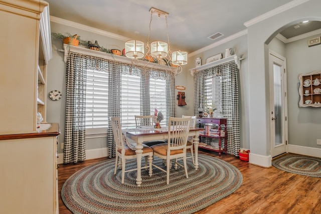 dining space with a notable chandelier, hardwood / wood-style flooring, and ornamental molding