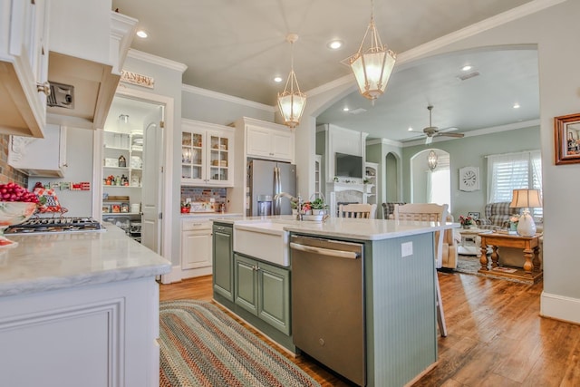 kitchen with white cabinets, a kitchen bar, stainless steel appliances, a center island with sink, and light wood-type flooring