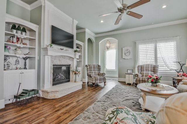 living room with crown molding, ceiling fan, a high end fireplace, and wood-type flooring