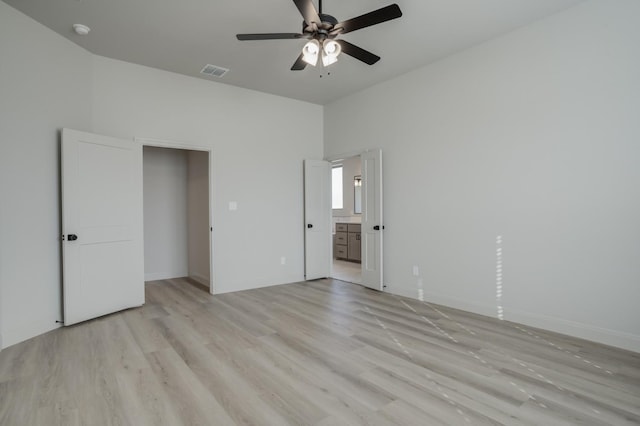 unfurnished bedroom with ceiling fan, ensuite bathroom, and light hardwood / wood-style floors