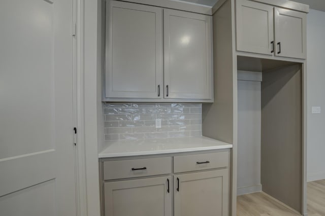 kitchen with gray cabinets, backsplash, and light hardwood / wood-style floors