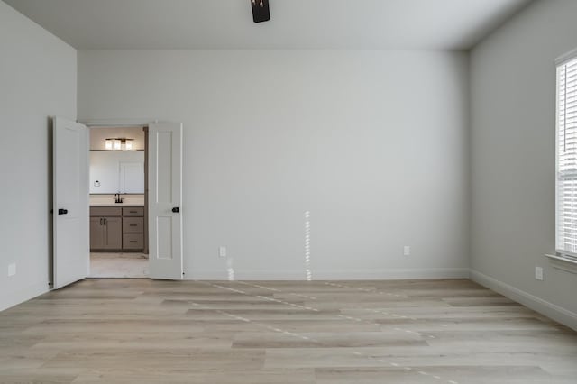 unfurnished room featuring sink, light hardwood / wood-style flooring, and ceiling fan