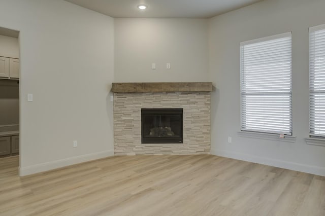 unfurnished living room featuring a stone fireplace and light hardwood / wood-style floors