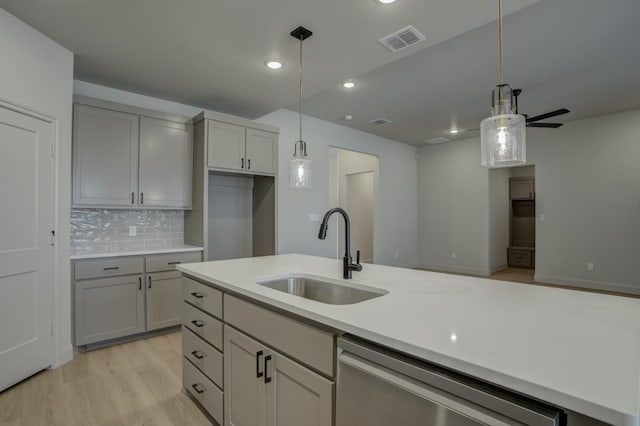 kitchen featuring pendant lighting, sink, gray cabinets, light hardwood / wood-style flooring, and dishwasher