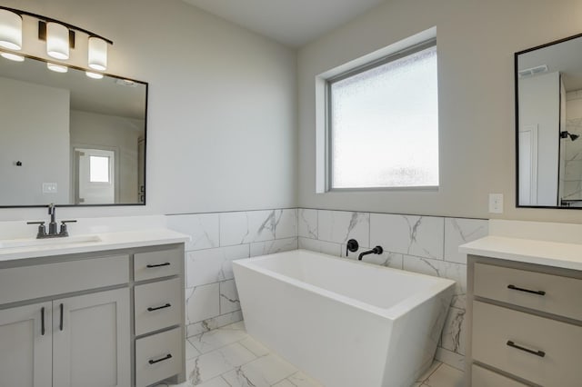 bathroom with vanity, a tub, and tile walls