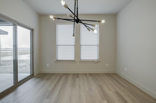 unfurnished dining area featuring a healthy amount of sunlight, a notable chandelier, and light hardwood / wood-style floors