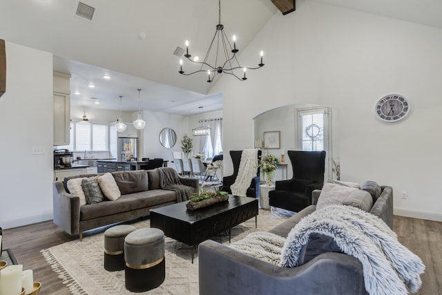 living room with baseboards, visible vents, a notable chandelier, and light wood finished floors