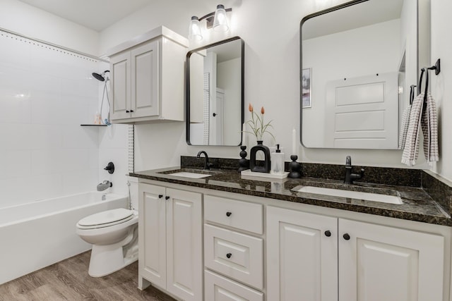 bathroom featuring wood finished floors, toilet, shower / washtub combination, and a sink