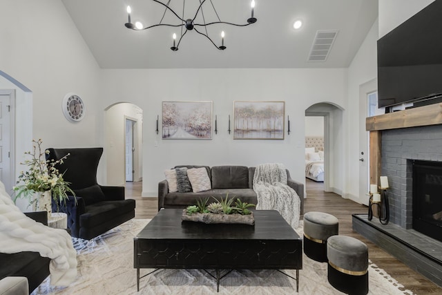 living room featuring a fireplace, wood finished floors, visible vents, and arched walkways